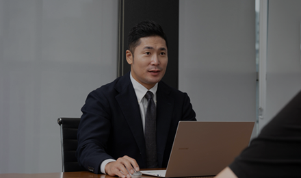 회의 테이블에서 노트북을 보는 정장 차림 사람